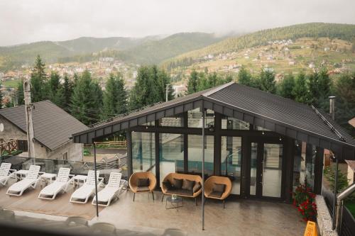 a building with chairs and a pool with mountains in the background at WhiteWood Cottages in Bukovel