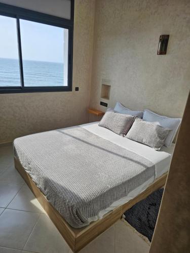 a bedroom with a bed with a view of the ocean at Amouage résidence 3 in Sidi Ifni