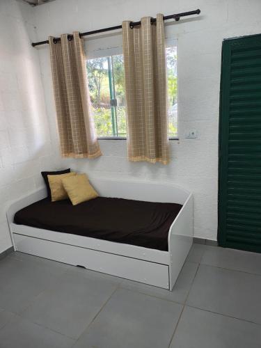 a bed in a room with two windows at Chalé do Mamute in Atibaia