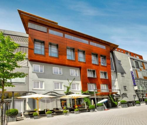 a large building with umbrellas in front of it at Hotel City Krone in Friedrichshafen