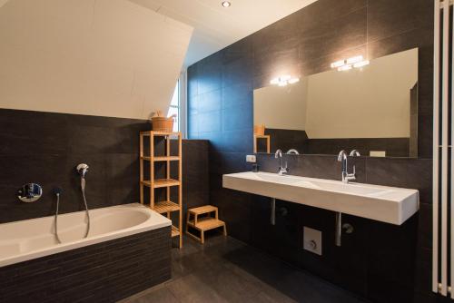 a bathroom with two sinks and a tub and a mirror at Luxe Duinvilla Stern met sauna voor 8 personen nabij strand en dorp Nes in Buren
