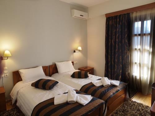 two beds in a hotel room with towels on them at Archontiko Tzoumerkon in Agnanta