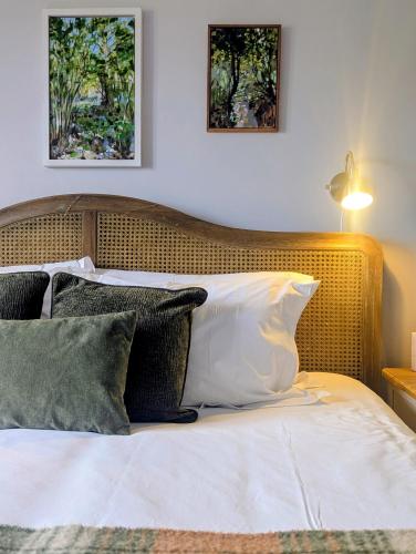 a bed with a wooden headboard and pillows at The Jolly Sportsman in Lewes