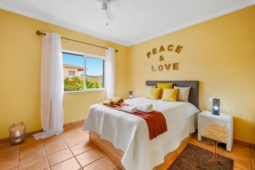 a bedroom with a bed with a sign that reads peace and love at "Orange Tree Villa in Alvor - South - facing Family Villa with Private Poll" in Alvor