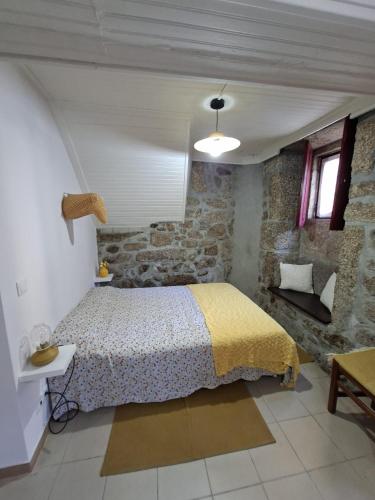a bedroom with a bed and a stone wall at Big Alface - Casa de Cima in Trinta