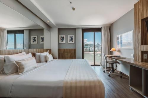a bedroom with a large white bed and a desk at Pestana Rio Atlantica in Rio de Janeiro