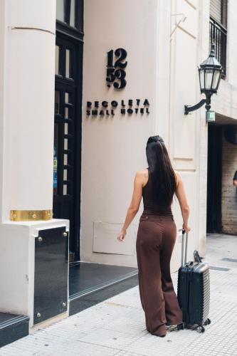 a woman standing on a street with a suitcase at 1253 Recoleta Small Hotel in Buenos Aires