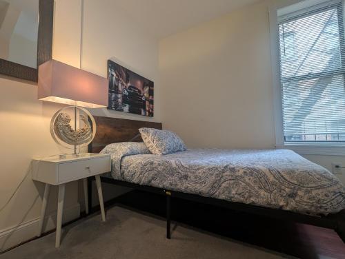 a bedroom with a bed and a lamp and a window at MANHATTAN ROSE Homestay in New York