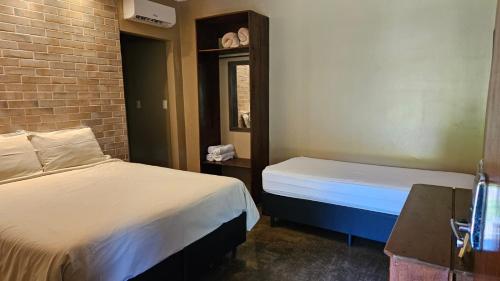 a bedroom with two beds and a brick wall at Villa Ayê Socorro SP - Pousada Petfriendly in Socorro