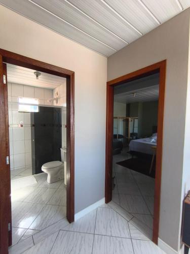 a room with a bathroom with a toilet and a bedroom at Aconchego do Lar Hostel in Palhoça