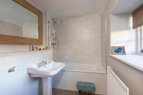 a white bathroom with a sink and a bath tub at Sandpiper Alnmouth in Alnmouth