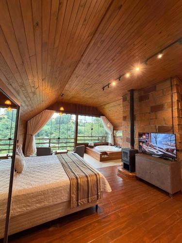 a large bedroom with a large bed and a tv at Chalé Vicenza in Marques de Sousa