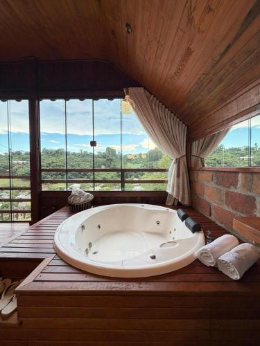 a large bath tub in a room with windows at Chalé Vicenza in Marques de Sousa