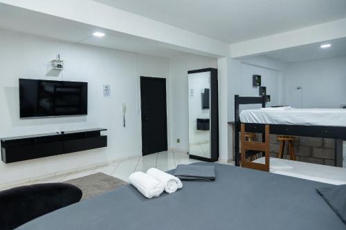 a living room with a bed and a tv and a bedroom at Quitinete Moderna Centro Loft Studio Inteligente 5 in Presidente Prudente