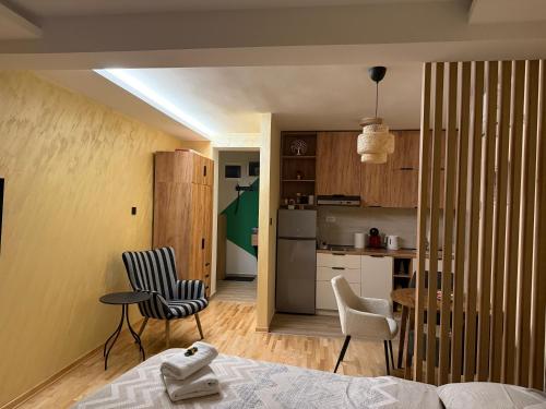 a room with a bed and chairs and a kitchen at PRESTIGE studio Krusevac in Kruševac