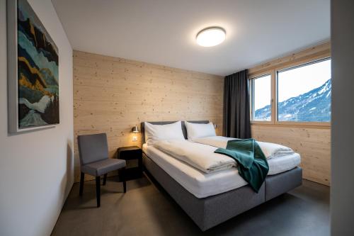 a bedroom with a bed with a chair and a window at Residenza Pazzola in Disentis