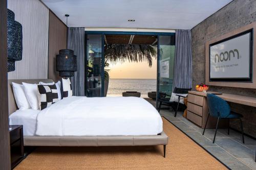 a bedroom with a bed and a desk and a view of the ocean at Noom Hotel Dakar Sea Plaza, a member of Radisson Individuals in Dakar