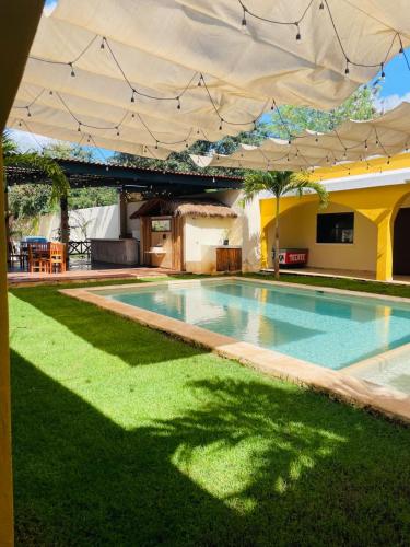 an outdoor swimming pool with an umbrella and grass at Hotel Villa Chucum in Valladolid