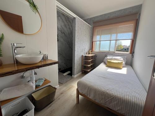 a bathroom with a bed and a sink and a mirror at Grace House Quarto single privado in Belinho