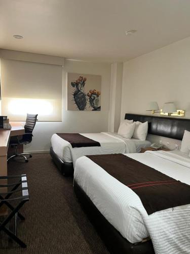 a hotel room with two beds and a desk at Hotel VM Express Queretaro in Mendiola