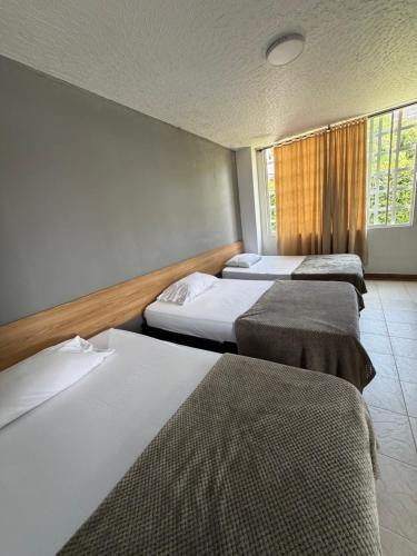 a room with three beds and a window at Hotel restaurante hortencia in La Mesa