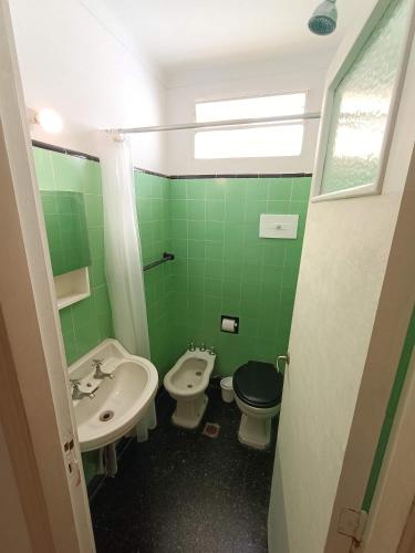 a green bathroom with a sink and a toilet at Casa Nanet Hotel in Mar del Plata