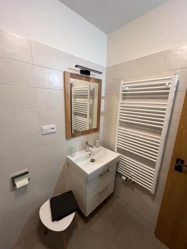 a white bathroom with a sink and a mirror at Apartmán Blatka in Nová Pec