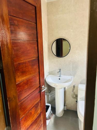 a bathroom with a wooden door and a sink at Tiwi's Travellers Inn - Solar Powered, Starlink, Scooter Rental, Palawan Tours in Puerto Princesa City