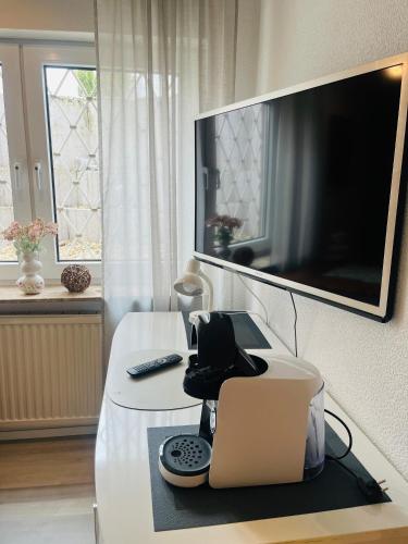 a living room with a white table with a television on a wall at Ferienwohnung am Weinberg in Flonheim