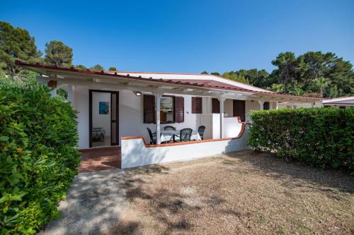 a small white house with a hedge at Villaggio Turistico Grotta dell'Acqua in Peschici