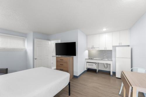 a bedroom with a bed and a desk and a kitchen at Birch Hill Suites Jackson in Jackson