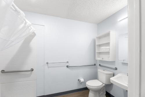a white bathroom with a toilet and a sink at Birch Hill Suites Jackson in Jackson