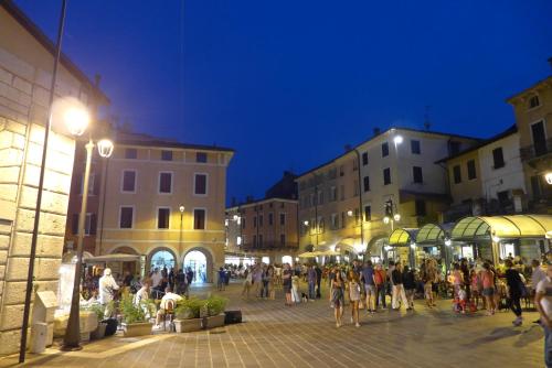 a group of people walking around a street at night at Alessi Appartamenti in Desenzano del Garda