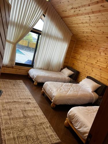 three beds in a room with a window at أكواخ غصُن عجلون in Ajloun