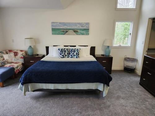 a bedroom with a bed with a blue blanket and two windows at Creekside Oasis in Lusby