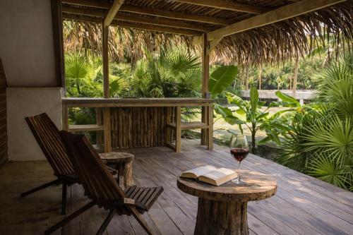 a wooden porch with a table and a glass of wine at Kin Resort Lodge in Maya Beach