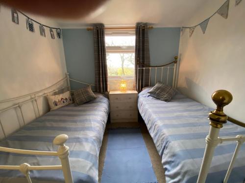 two twin beds in a room with a window at 49 Erw Porthor in Tywyn