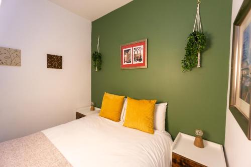 a bedroom with green walls and a bed with yellow pillows at Cozy flat by Birmingham Canals & City Centre in Birmingham