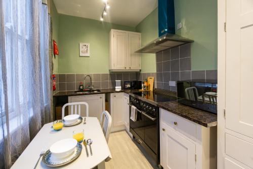 a small kitchen with a white table and a stove at Cozy flat by Birmingham Canals & City Centre in Birmingham