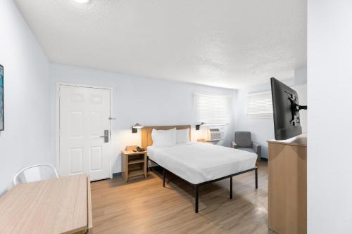 a bedroom with a bed and a desk and a tv at Birch Hill Suites Jackson in Jackson