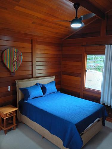 a bedroom with a blue bed in a room with wooden walls at Chalés da Preguiça in Pedra Menina