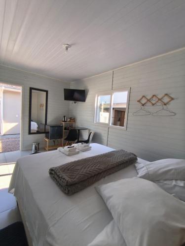 a bedroom with a large white bed and a television at Aconchego do Lar Hostel in Palhoça