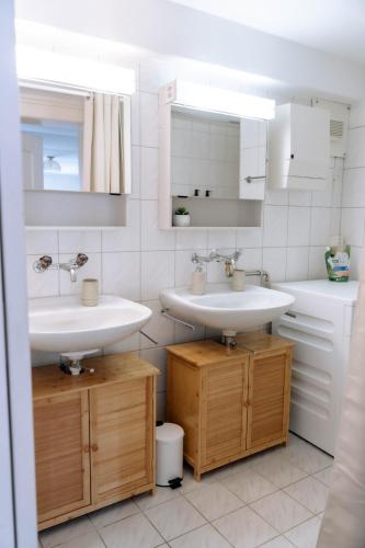 a white bathroom with two sinks and a toilet at Cara Nima Schwyz in Schwyz