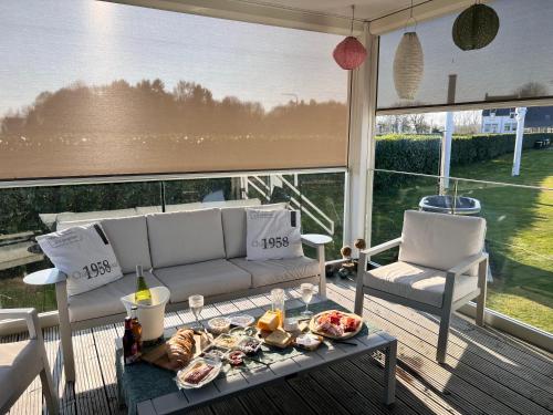 a living room with a couch and a table with food at Maasparcje Lodge met Hottub,kamadoBBQ en FirePit in Roermond