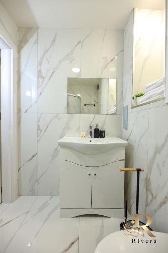 a white bathroom with a sink and a mirror at Apartments Rivera in Dobrich