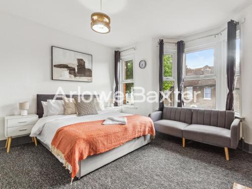 a bedroom with a bed and a couch and windows at East LDN Guest Rooms and Amenities in London