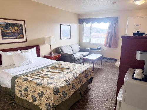 a hotel room with a bed and a couch at Travelodge by Wyndham Drumheller AB in Drumheller