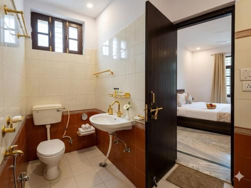 a bathroom with a toilet and a sink and a bed at Heritage Inn Gomti Nagar in Lucknow