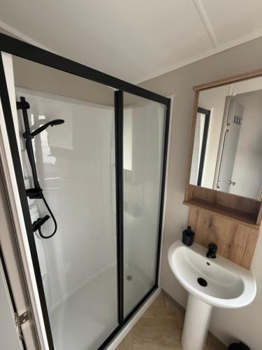 a bathroom with a glass shower and a sink at Luxury 3 bed sleeps 8 caravan with sea view in Exmouth