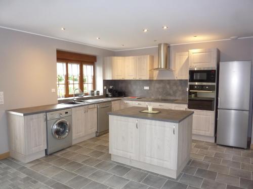 une cuisine avec des armoires blanches et des appareils en acier inoxydable dans l'établissement Le Courtil, à Buironfosse